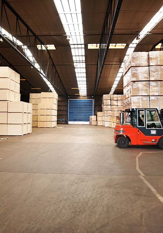 A large warehouse storing big boxes with a forklift.